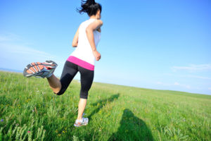 Runner athlete legs running on grass seaside